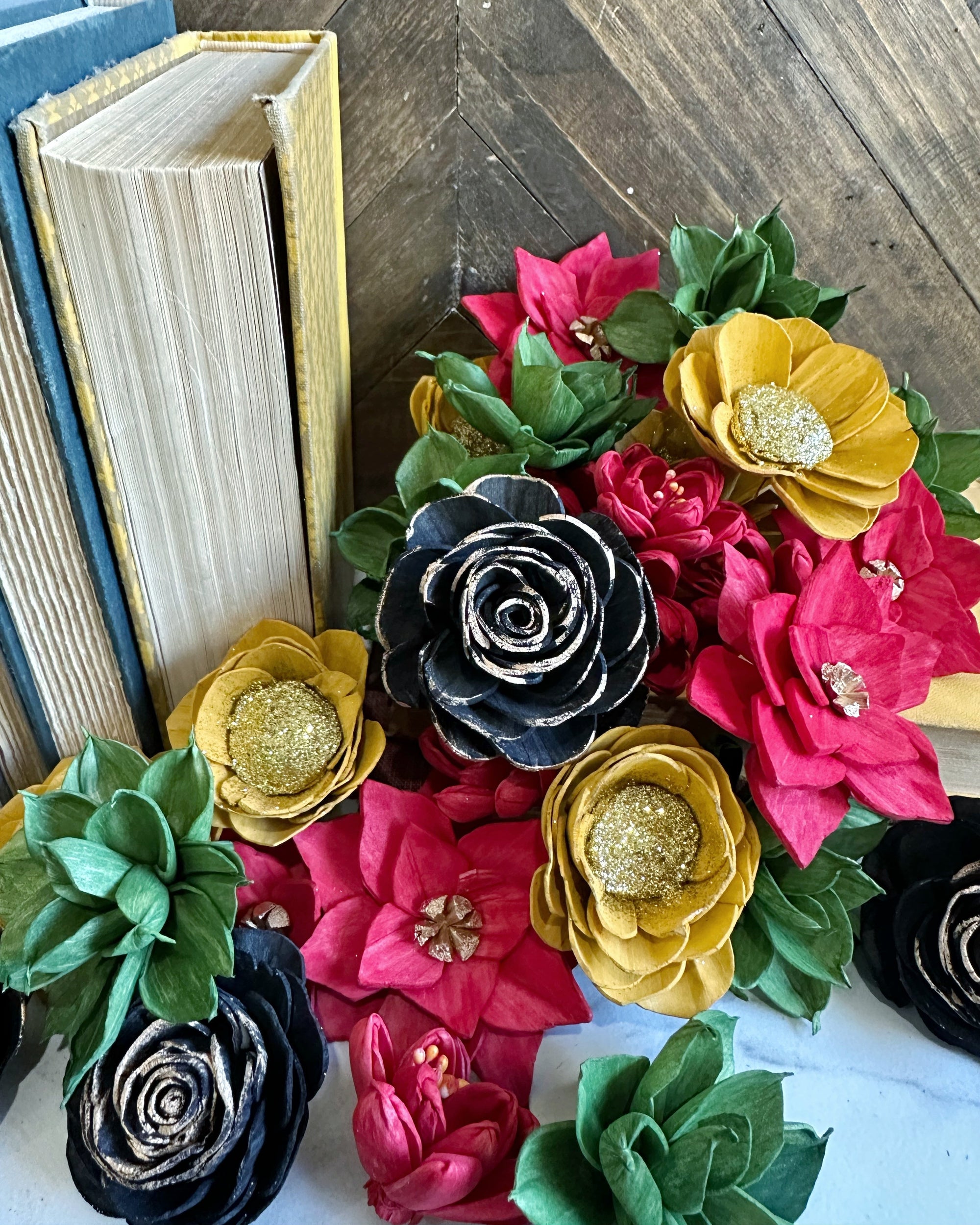 Colorful flower-shaped objects on a wooden surface with books in the background